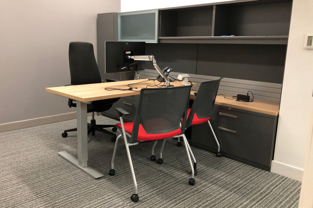 A small desk with three office chairs