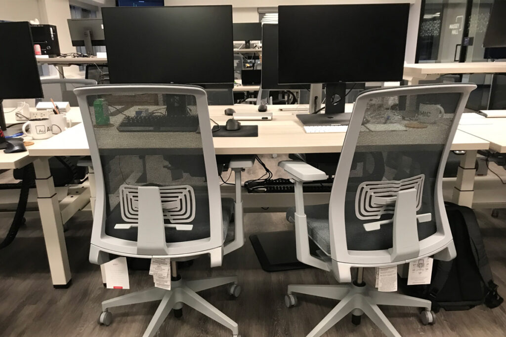 Two office chairs at a desk with two monitors