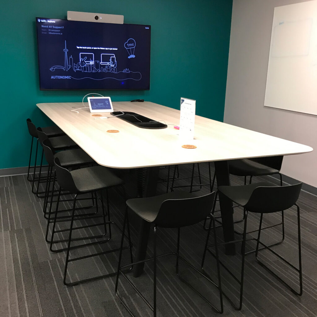 Meeting room with a monitor on the wall and a small table with lots of chairs